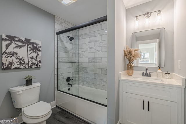 bathroom featuring vanity, toilet, baseboards, combined bath / shower with glass door, and wood finished floors