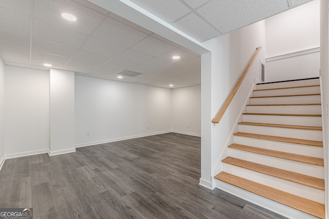 finished basement with stairs, recessed lighting, baseboards, a drop ceiling, and wood finished floors