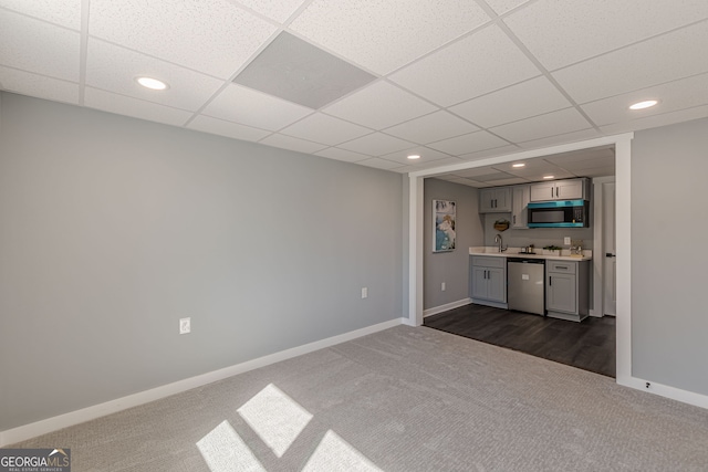 interior space featuring a sink, stainless steel dishwasher, indoor wet bar, baseboards, and dark carpet