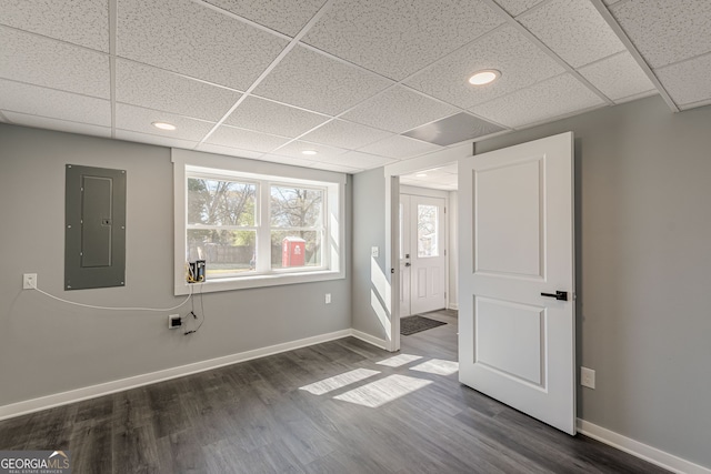 unfurnished bedroom with electric panel, baseboards, dark wood finished floors, and a drop ceiling