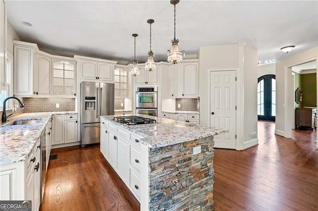 3795 Duckcove Way, Cumming, GA 30041 - kitchen with appliances with stainless steel finishes, a sink, a center island, arched walkways, and dark wood-type flooring
