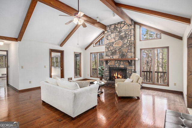living area featuring baseboards, a ceiling fan, a wealth of natural light, and a stone fireplace