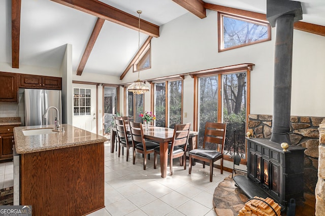 dining room with beam ceiling, light tile patterned flooring, high vaulted ceiling, and a wood stove