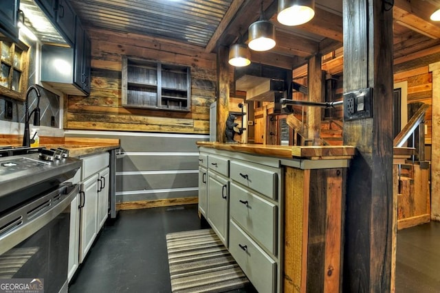kitchen with green cabinets, stainless steel stove, wooden walls, baseboards, and hanging light fixtures