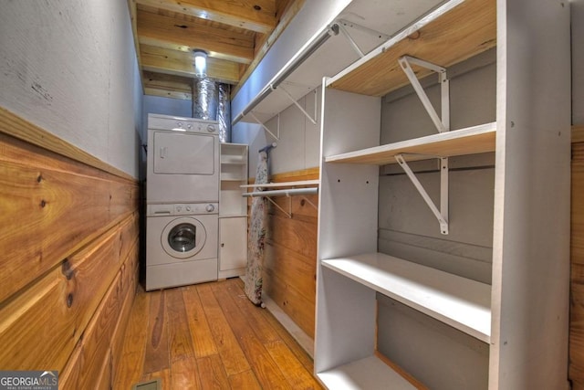 clothes washing area with stacked washer and dryer and light wood finished floors