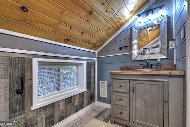 bathroom with vanity, wood walls, lofted ceiling, wood ceiling, and visible vents