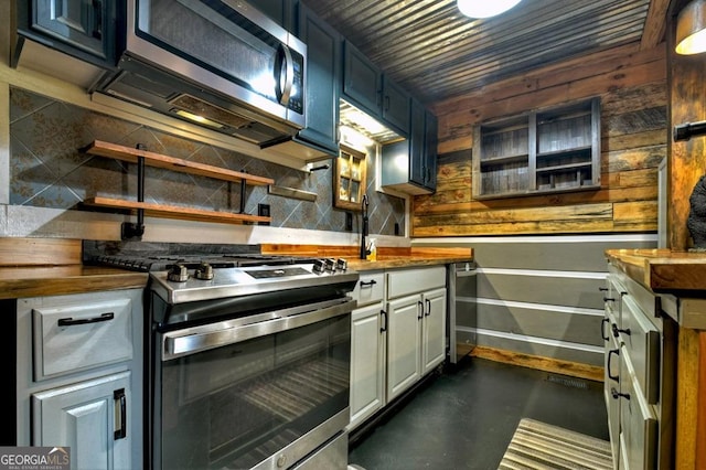 kitchen featuring decorative backsplash, baseboards, butcher block counters, appliances with stainless steel finishes, and a sink