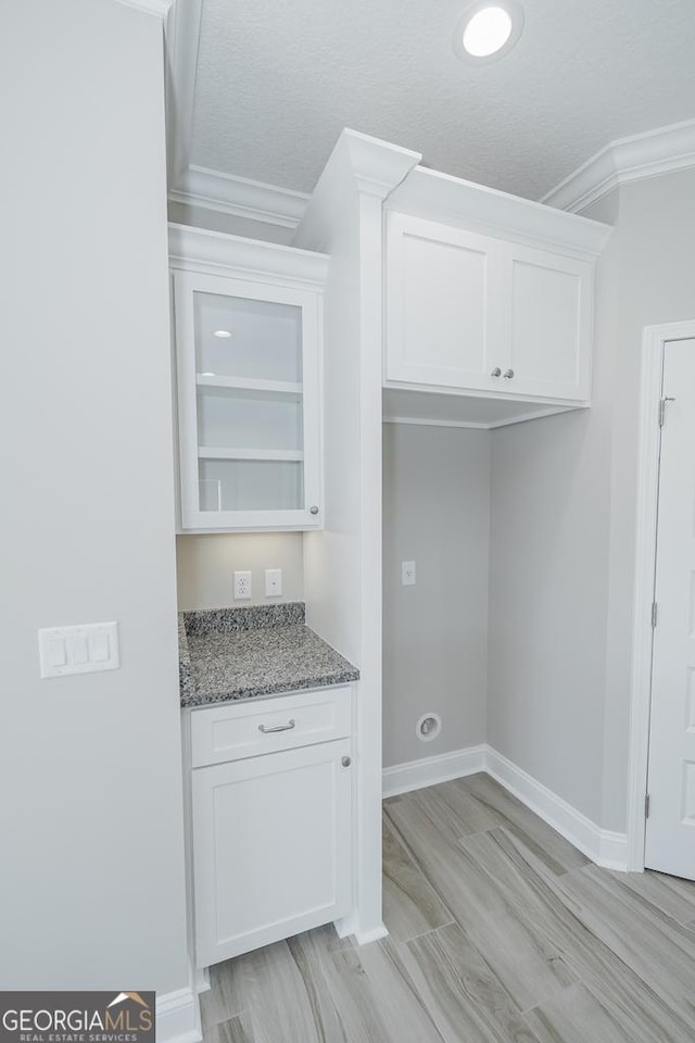 114 Richard Lee Dr, Kingsland, GA 31548 - kitchen with ornamental molding, white cabinets, light stone counters, light wood-style flooring, and glass insert cabinets