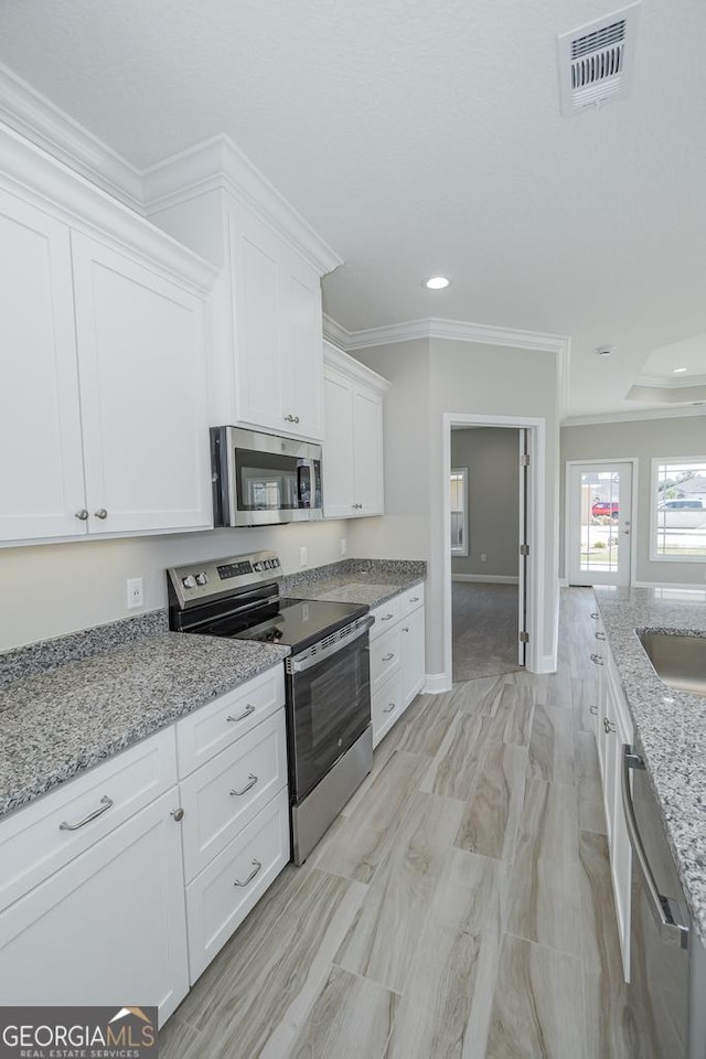 114 Richard Lee Dr, Kingsland, GA 31548 - kitchen with appliances with stainless steel finishes, white cabinetry, recessed lighting, crown molding, and light stone counters