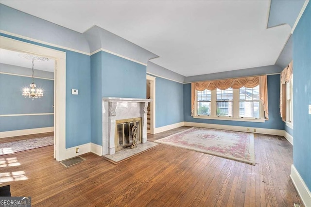 2265 E Lake Rd NE, Atlanta, GA 30307 - unfurnished living room featuring visible vents, baseboards, a tiled fireplace, hardwood / wood-style floors, and a notable chandelier