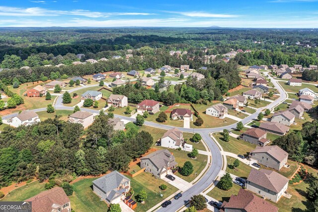 drone / aerial view featuring a wooded view and a residential view