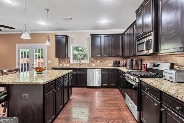 kitchen with appliances with stainless steel finishes, plenty of natural light, a kitchen bar, and a sink