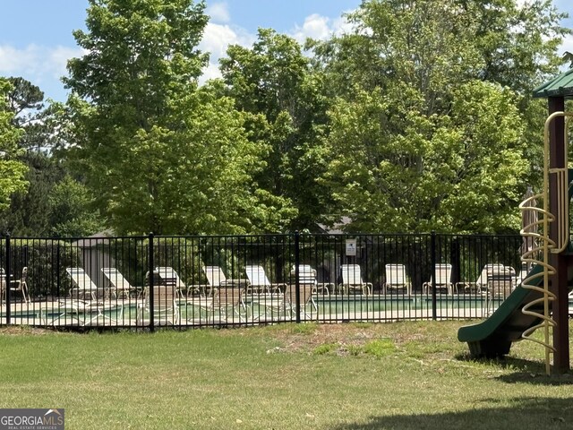 exterior space with a pool, fence, and a lawn