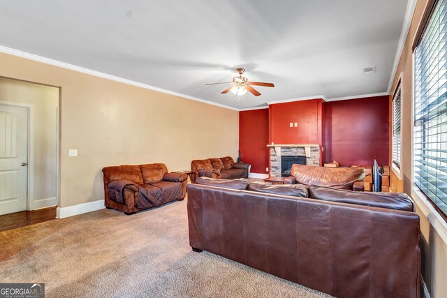 carpeted living area featuring crown molding, baseboards, a fireplace, and a ceiling fan