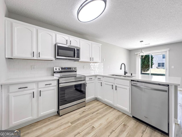 7229 Georges Way, Morrow, GA 30260 - kitchen with light wood-type flooring, stainless steel appliances, a sink, white cabinets, and a peninsula