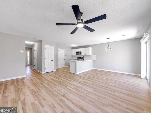 7229 Georges Way, Morrow, GA 30260 - unfurnished living room with a sink, a ceiling fan, light wood finished floors, a textured ceiling, and baseboards