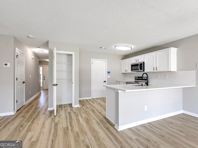 7229 Georges Way, Morrow, GA 30260 - kitchen with light countertops, stainless steel appliances, white cabinetry, a sink, and light wood-type flooring