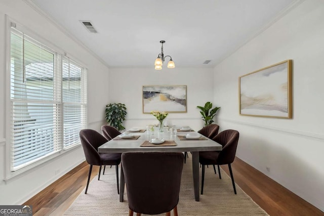 7503 Brookstone Cir, Flowery Branch, GA 30542 - dining room with a notable chandelier, crown molding, wood finished floors, baseboards, and visible vents