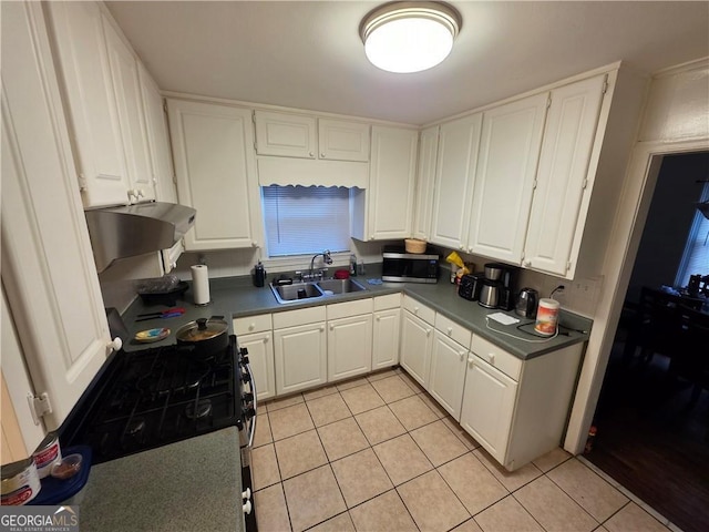 kitchen featuring white cabinetry, under cabinet range hood, a sink, and light tile patterned floors