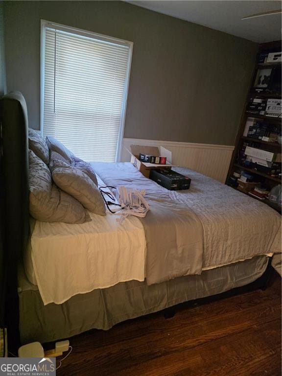 bedroom with wood finished floors and wainscoting