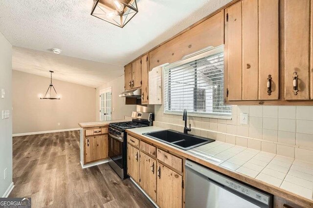kitchen featuring stainless steel appliances, under cabinet range hood, decorative backsplash, a sink, and tile countertops