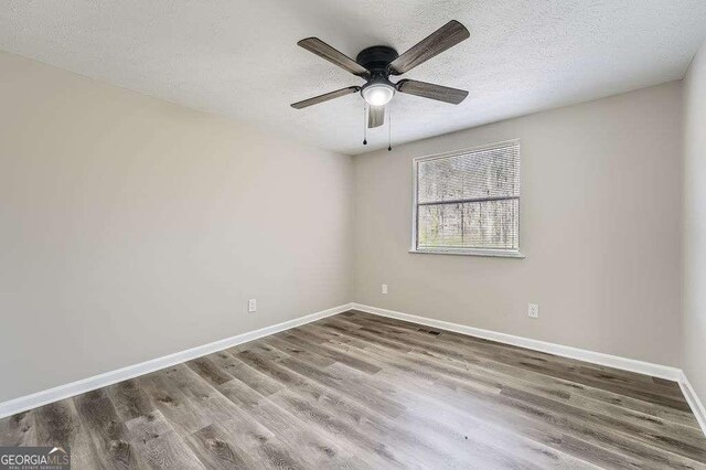 unfurnished bedroom with baseboards, a textured ceiling, visible vents, a ceiling fan, and wood finished floors