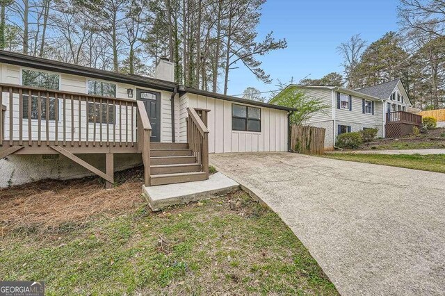 view of front of house featuring a chimney, a front yard, fence, and concrete driveway