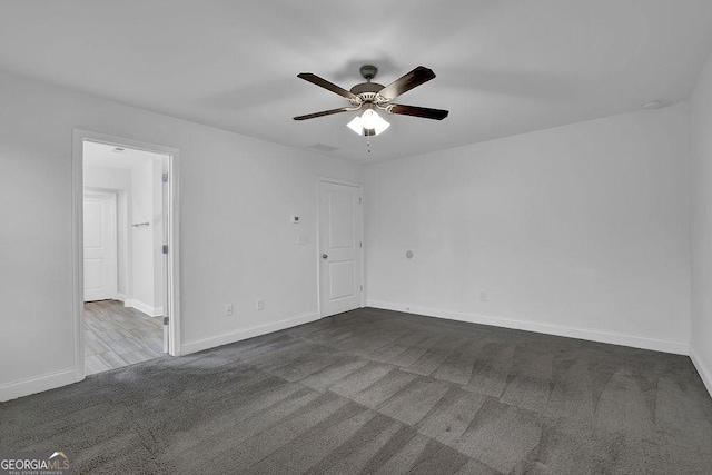 spare room with dark colored carpet, baseboards, and a ceiling fan