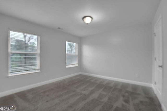 spare room featuring baseboards and dark colored carpet