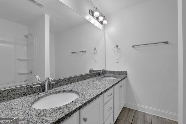 full bath featuring a sink, visible vents, baseboards, and double vanity
