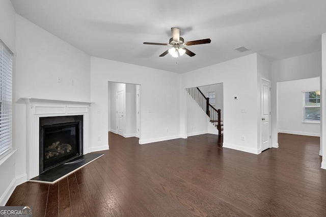 unfurnished living room featuring baseboards, stairs, visible vents, ceiling fan, and wood finished floors