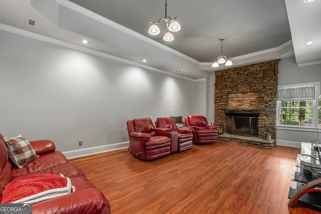 2977 Glover Dr, Cumming, GA 30040 - living area featuring wood-type flooring, a tray ceiling, a chandelier, crown molding, and a stone fireplace