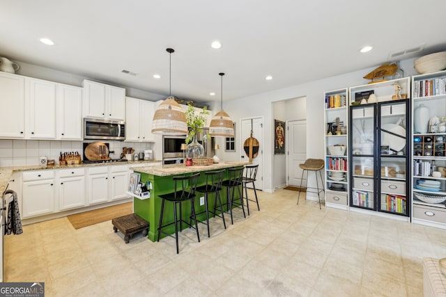 5225 Tye Trl, Fairburn, GA 30213 - kitchen featuring stainless steel appliances, white cabinetry, tasteful backsplash, light stone counters, and a kitchen breakfast bar