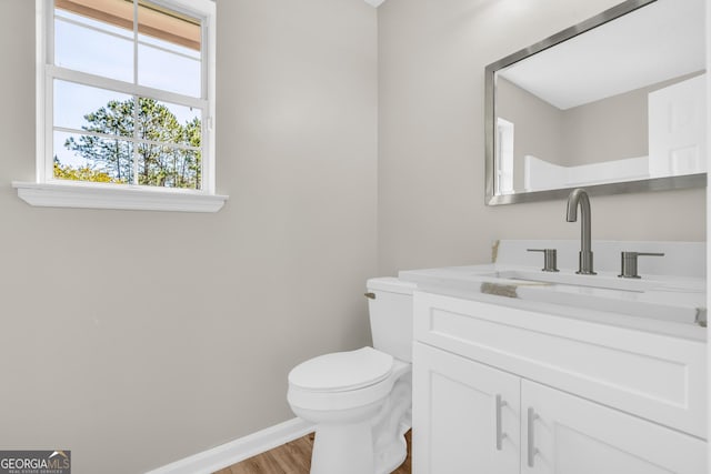 bathroom featuring toilet, vanity, wood finished floors, and baseboards