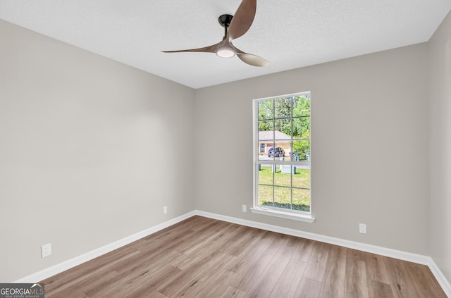 unfurnished room featuring baseboards, a ceiling fan, wood finished floors, and a textured ceiling