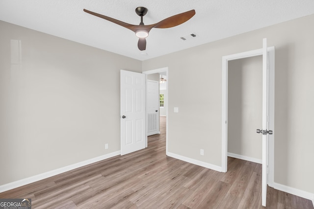 unfurnished bedroom featuring ceiling fan, baseboards, light wood-style floors, and visible vents