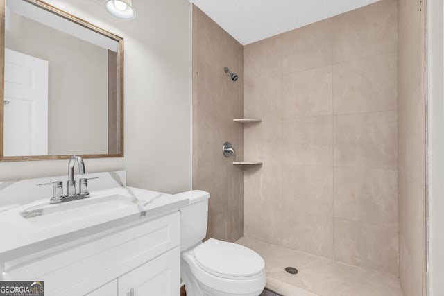 bathroom featuring a tile shower, vanity, and toilet