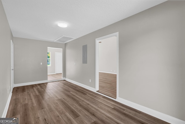 unfurnished room with baseboards, wood finished floors, electric panel, and a textured ceiling