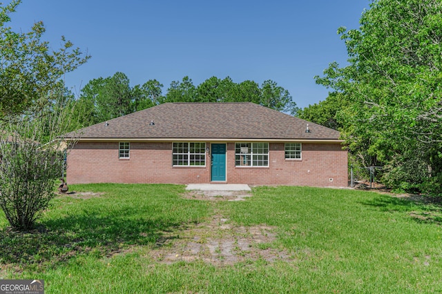 rear view of house with brick siding and a yard