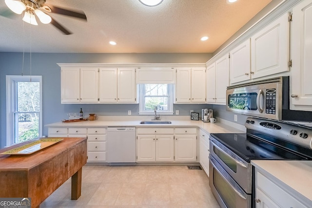 kitchen with stainless steel appliances, a sink, light countertops, white cabinetry, and recessed lighting