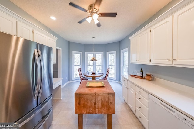 kitchen with freestanding refrigerator, white dishwasher, light countertops, white cabinets, and a textured ceiling