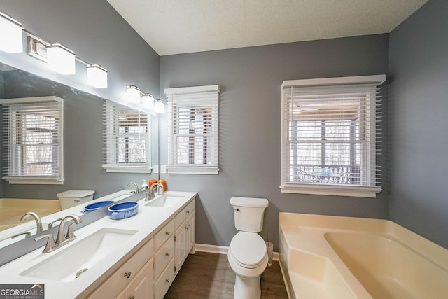 bathroom with toilet, a bath, baseboards, and wood finished floors