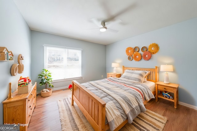 bedroom featuring light wood-type flooring, baseboards, and a ceiling fan