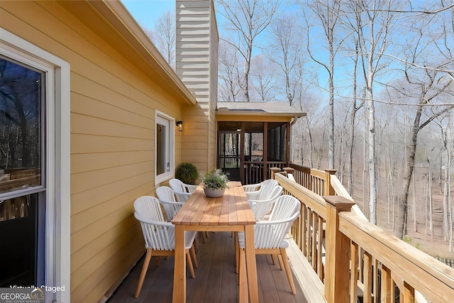 deck with a sunroom and outdoor dining space