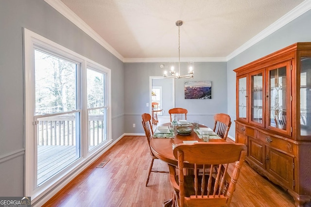 dining area with light wood-type flooring, a chandelier, ornamental molding, and baseboards
