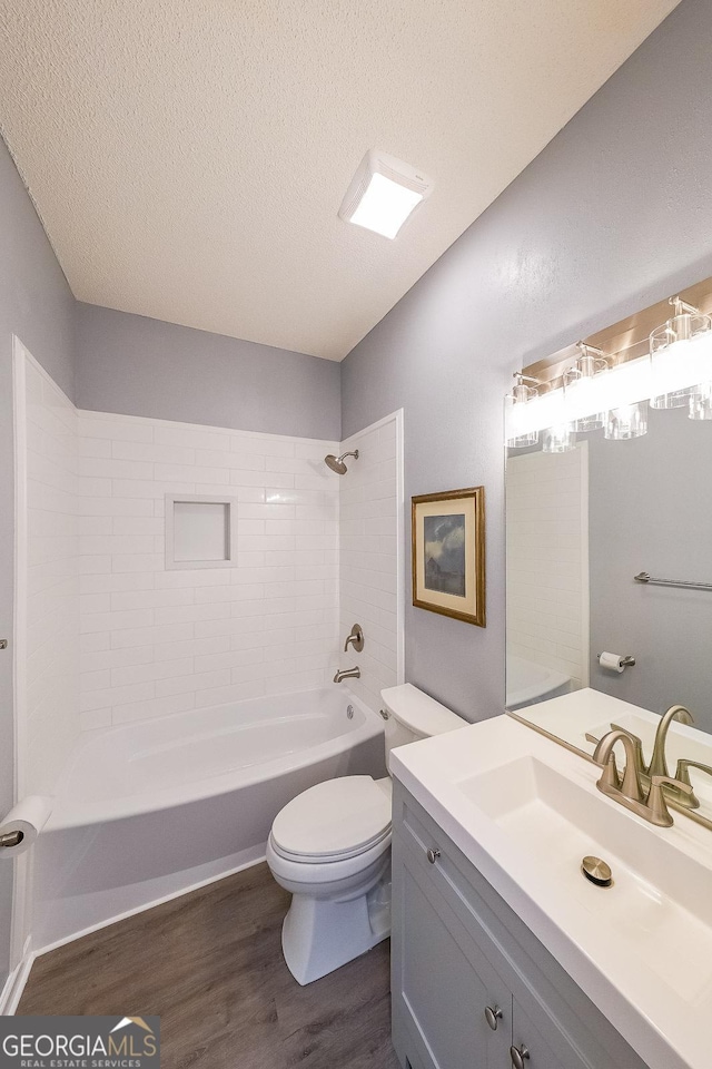 full bathroom with wood finished floors, toilet, tub / shower combination, a textured ceiling, and vanity