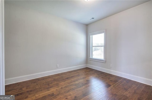 unfurnished room featuring visible vents, baseboards, and dark wood-type flooring