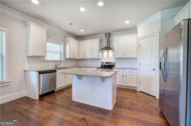 kitchen featuring stainless steel appliances, visible vents, white cabinetry, wall chimney range hood, and ornamental molding