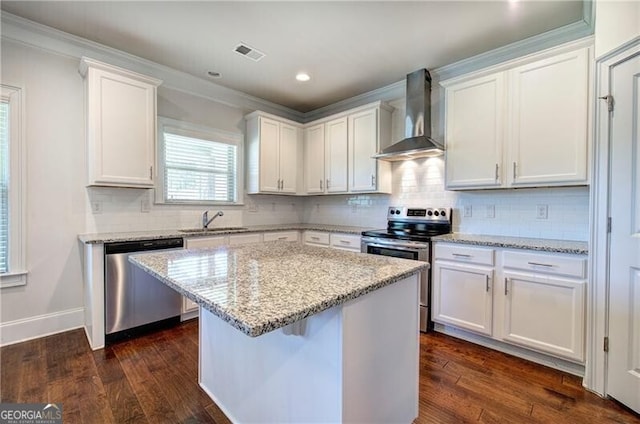 kitchen featuring a sink, visible vents, appliances with stainless steel finishes, wall chimney range hood, and ornamental molding