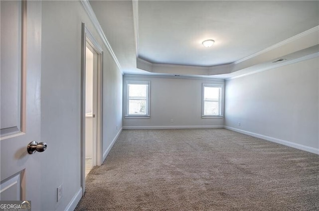 carpeted empty room with a raised ceiling, visible vents, crown molding, and baseboards